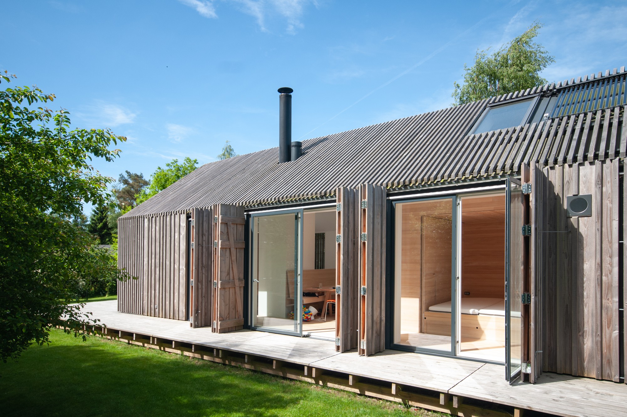 Sommerhusets træfacade og store åbninger mod haven